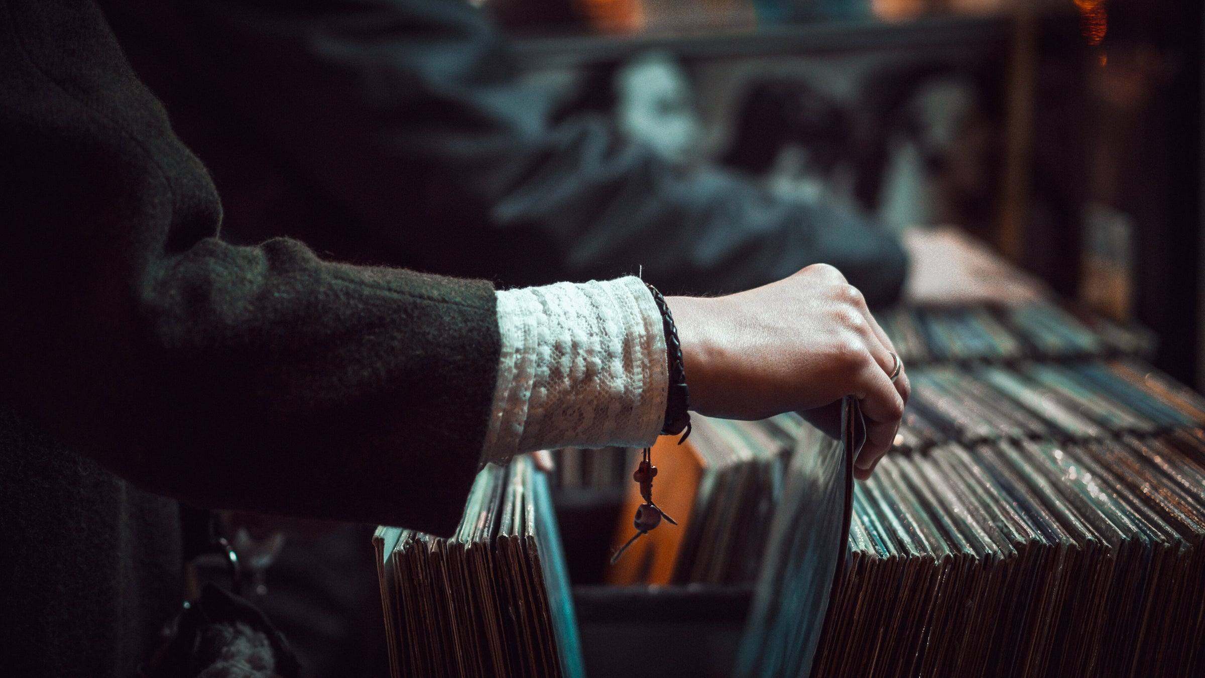 Una mano recorre una batea de discos de vinilo